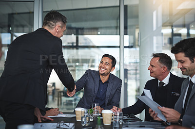 Buy stock photo Shot of two cheerful businessmen shaking hands in agreement in a boardroom at the office