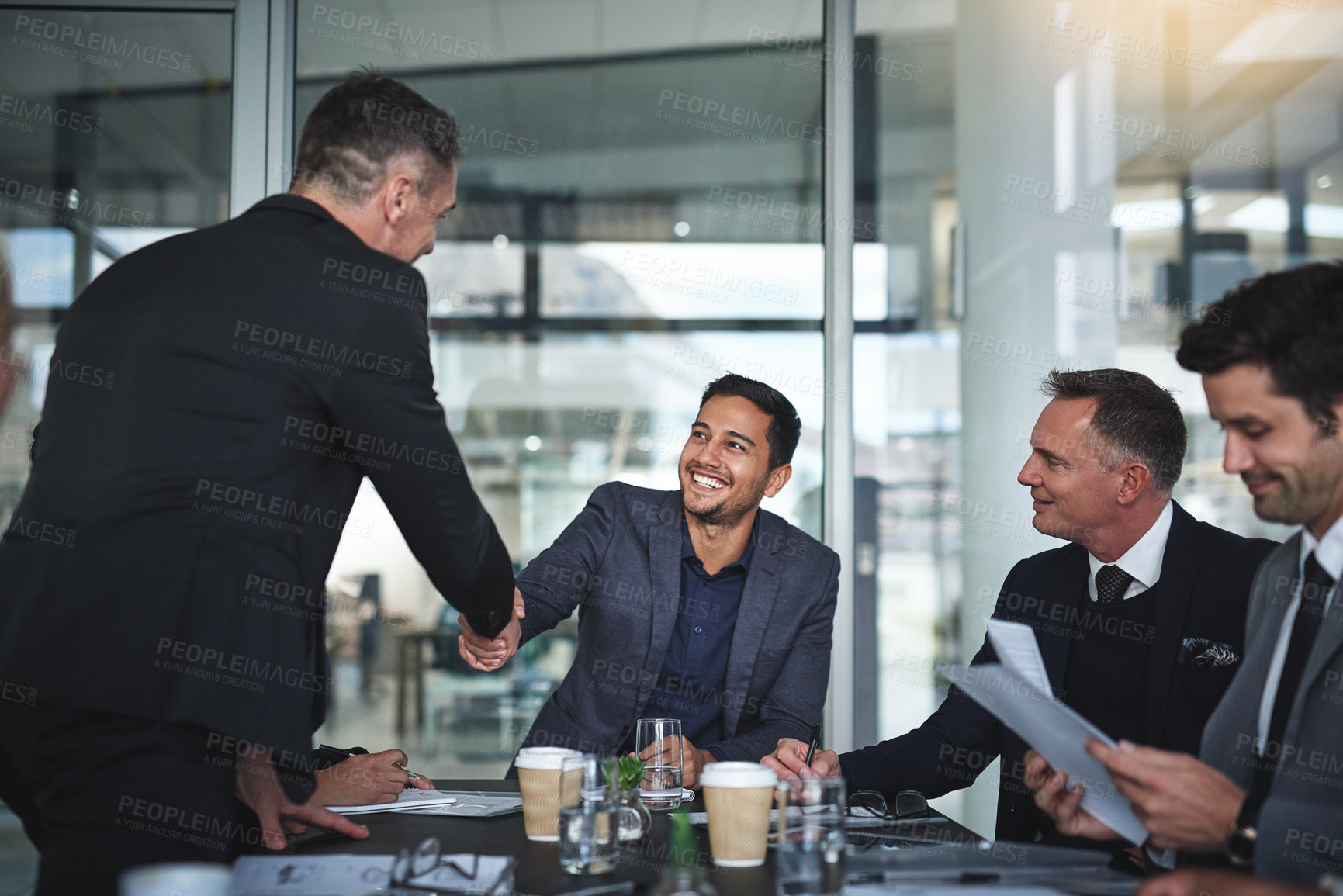 Buy stock photo Shot of two cheerful businessmen shaking hands in agreement in a boardroom at the office