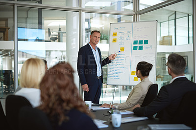 Buy stock photo Shot of a mature businessman explaining work related stuff during a presentation to work colleagues in a boardroom