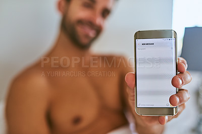 Buy stock photo Shot of a handsome young man holding a cellphone at home