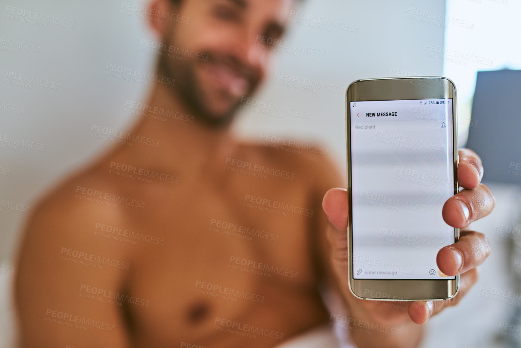 Buy stock photo Shot of a handsome young man holding a cellphone at home