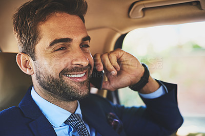 Buy stock photo Shot of a cheerful young businessman talking on his cellphone while being seated in the back of a car