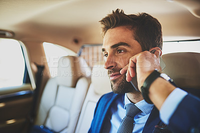 Buy stock photo Shot of a confident young businessman talking on his cellphone while being seated in the back of a car