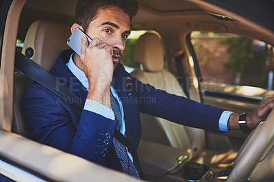 Buy stock photo Shot of a confident young businessman talking on his cellphone while driving his car