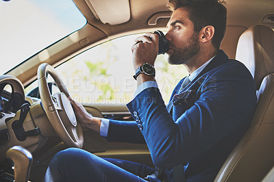 Buy stock photo Shot of a cheerful young businessman driving in his car to work while sitting in traffic and drinking coffee