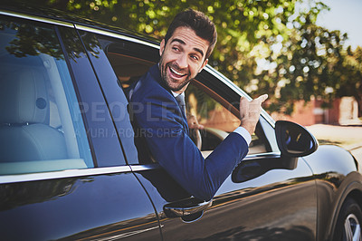 Buy stock photo Shot of a cheerful young businessman hanging out of a car window and pointing with his hand towards the front of his car