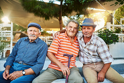 Buy stock photo Portrait of a group of cheerful senior men sitting together while looking into the camera outside