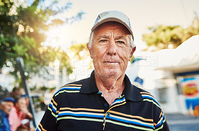Buy stock photo Portrait of a cheerful senior man wearing a hat and standing outside while looking at the camera