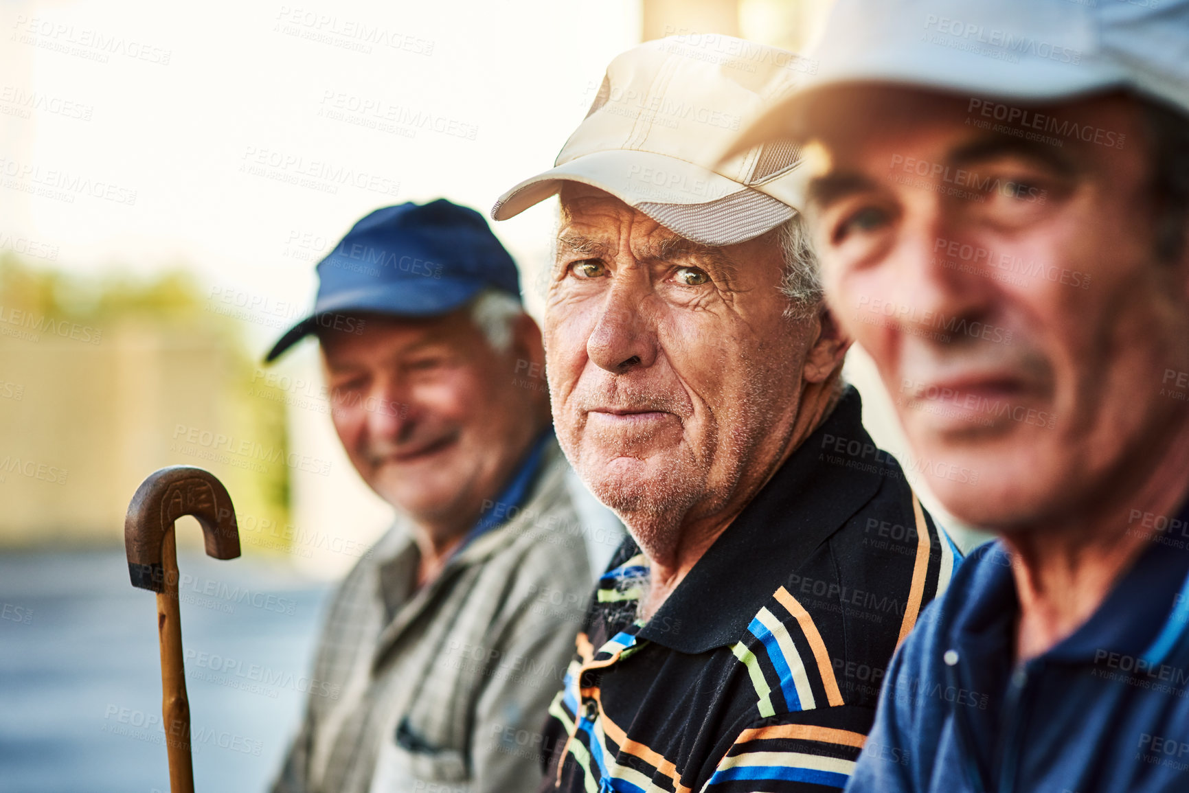 Buy stock photo Portrait of a group of cheerful senior men sitting together while looking into the camera outside