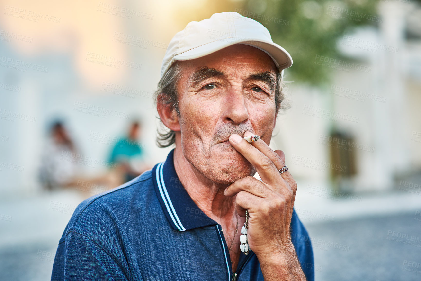 Buy stock photo Portrait of a cheerful senior man  smoking a cigarette and standing outside while looking at the camera