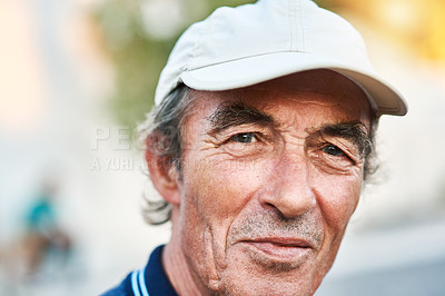 Buy stock photo Portrait of a cheerful senior man wearing a hat and standing outside while looking at the camera