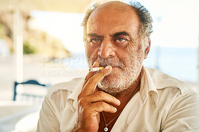 Buy stock photo Portrait of a confident senior man  smoking a cigarette and standing outside while looking at the camera