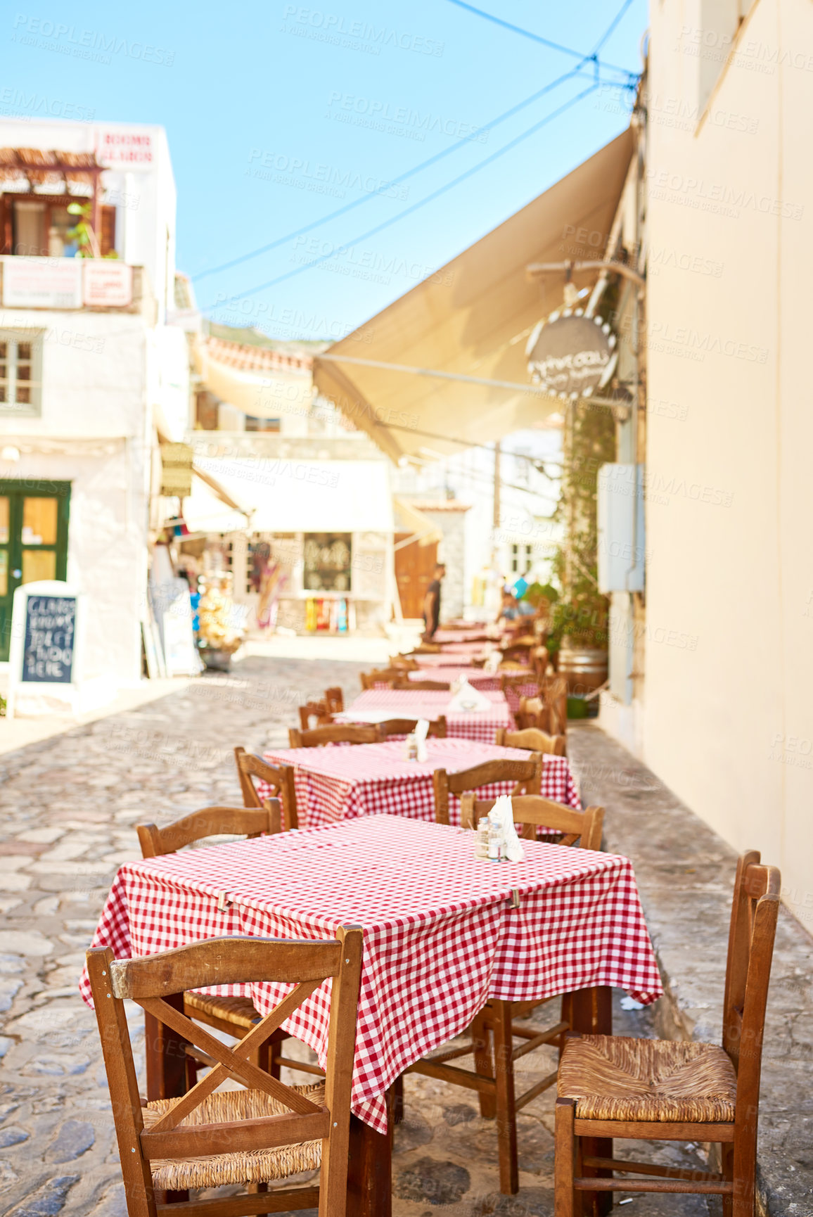 Buy stock photo Shot of a group of empty tables and chairs packed outside a restaurant during the day