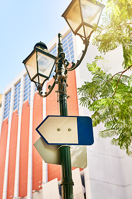 Buy stock photo Shot of a directional sign on a streetlamp outside during the day