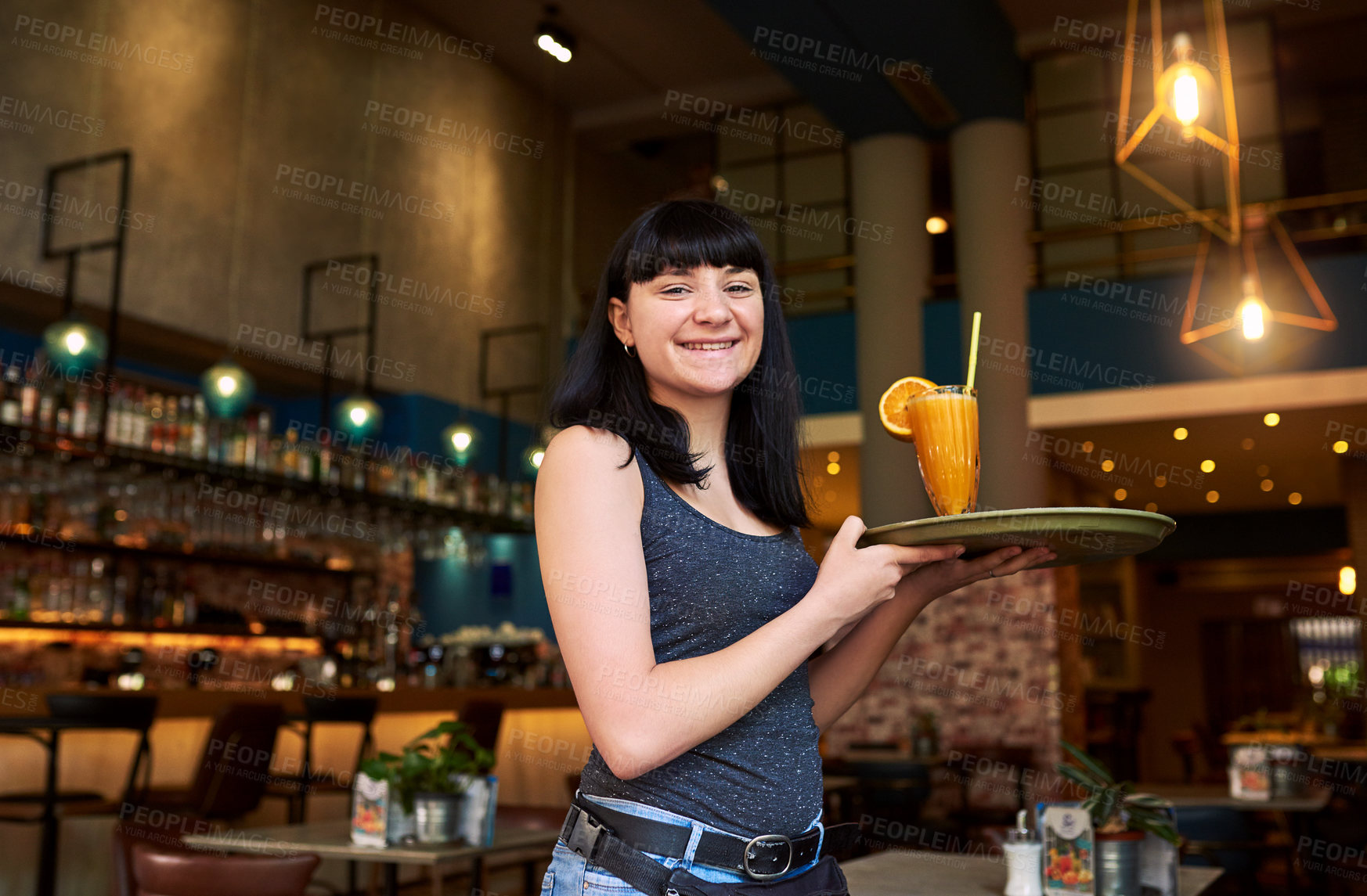 Buy stock photo Shot of a young waitress holding a tray with a drink on it at a bar
