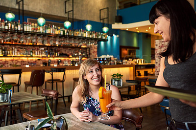 Buy stock photo Shot of a young waitress serving a drink to a female customer in a bar