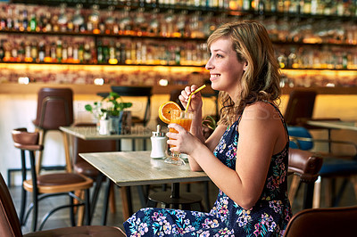 Buy stock photo Shot of a beautiful young woman enjoying a drink at a bar