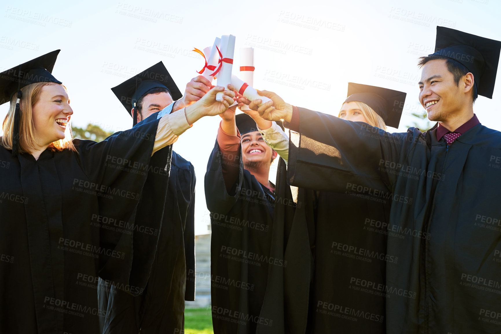 Buy stock photo Shot of a group of students holding their diplomas together on graduation day