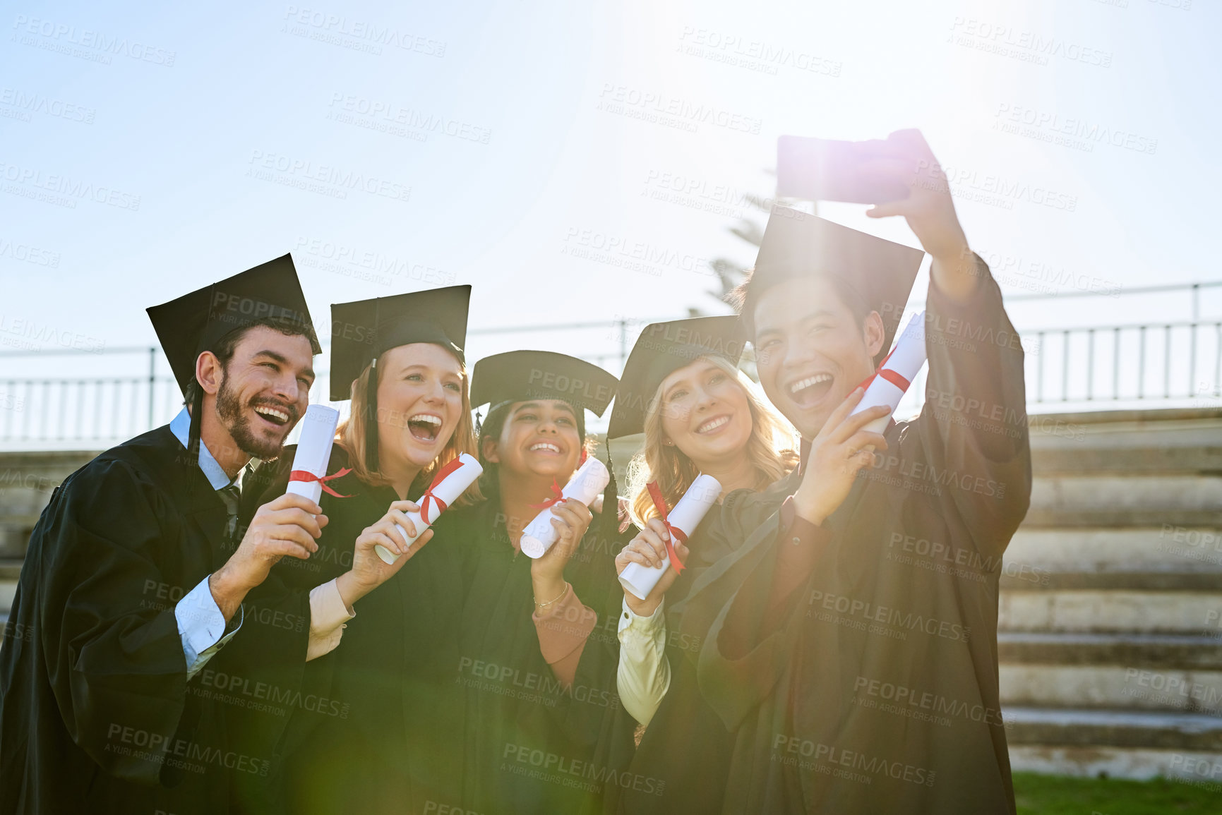 Buy stock photo Shot of a group of students taking a selfie together on graduation day