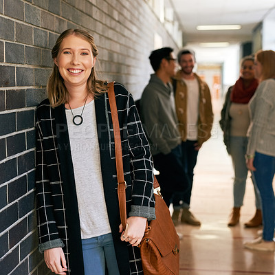 Buy stock photo Portrait of a young female university student standing in a campus corridor with her classmates in the background