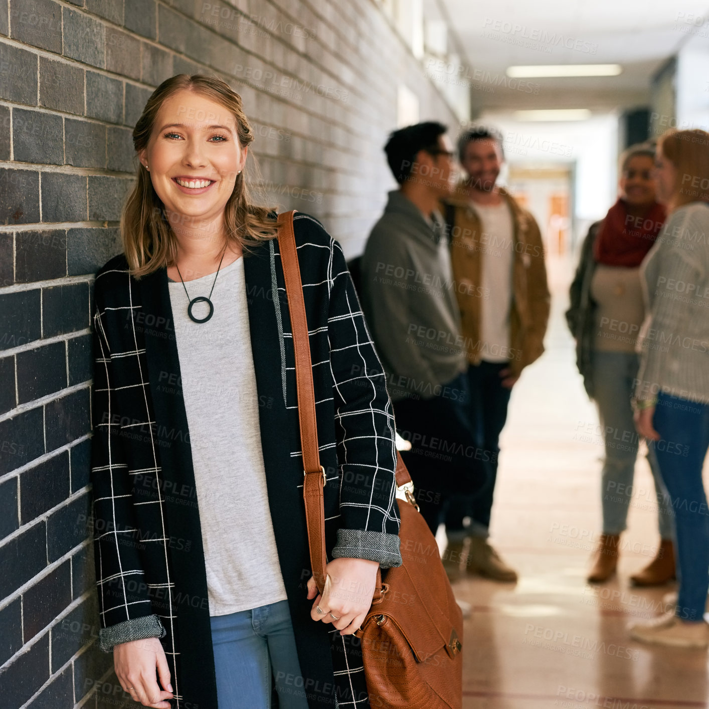 Buy stock photo Portrait of a young female university student standing in a campus corridor with her classmates in the background