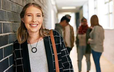 Buy stock photo Portrait of a young female university student standing in a campus corridor with her classmates in the background