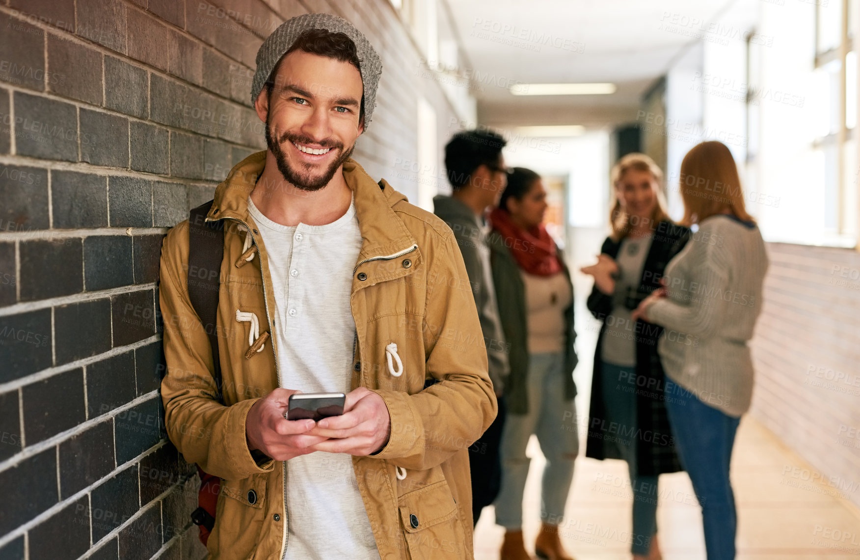 Buy stock photo Portrait of a young male university student standing in a campus corridor with his classmates in the background