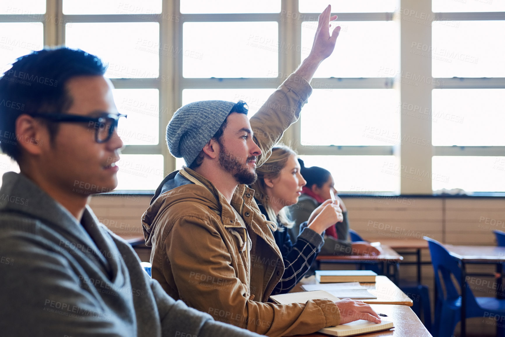 Buy stock photo University, raised hand and man student with classmates in lecture for question, knowledge or learning. Scholarship, education and male person with group for college exam, test or assignment tutoring