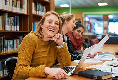 Buy stock photo Portrait of a cheerful young female student working on her laptop and studying inside of a library