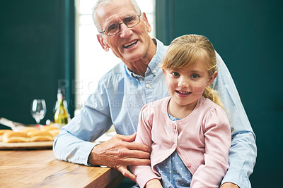 Buy stock photo Portrait of a cheerful elderly man and his little grand daughter playing around on a digital tablet next to a table at home