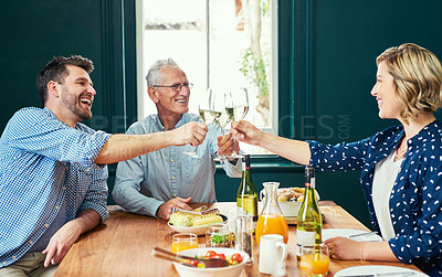Buy stock photo Shot of a cheerful family sharing a celebratory toast together while being seated around the dinner table at home