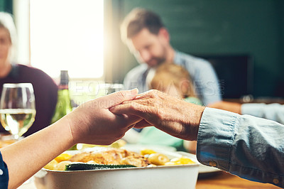 Buy stock photo Closeup of a peaceful family holding hands to say grace together around a dinner table at home