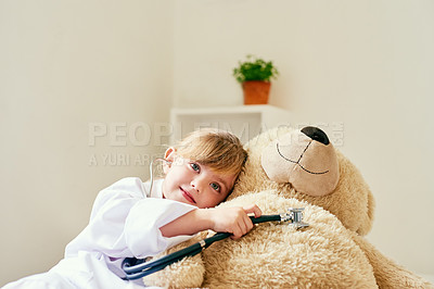 Buy stock photo Shot of an adorable little girl dressed up as a doctor and examining a teddy bear with a stethoscope