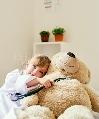 Buy stock photo Shot of an adorable little girl dressed up as a doctor and examining a teddy bear with a stethoscope