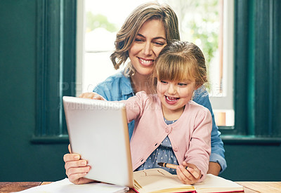 Buy stock photo Shot of a cheerful young mother and her young little daughter playing around on a digital tablet at home