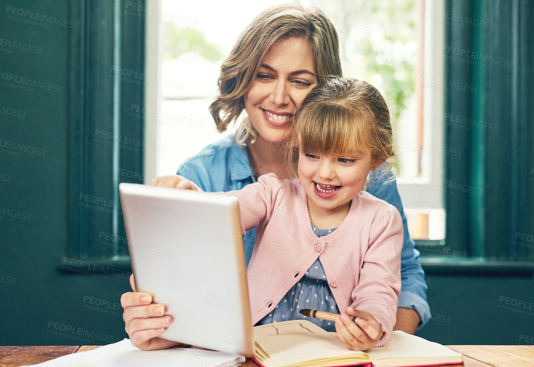 Buy stock photo Shot of a cheerful young mother and her young little daughter playing around on a digital tablet at home