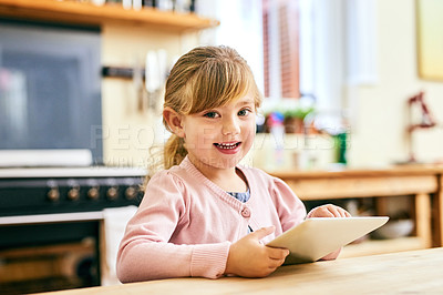 Buy stock photo Portrait of a cheerful little girl busy playing around on a digital tablet inside at home while looking at the camera