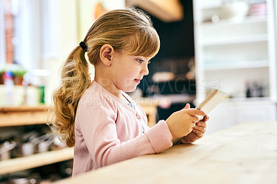 Buy stock photo Shot of a cheerful little girl busy playing around on a digital tablet inside at home