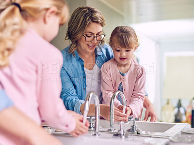 Buy stock photo Shot of a cheerful young mother and her young little daughter washing their hands together