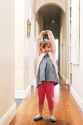 Buy stock photo Portrait of a cheerful little girl stretching her arms up in the air while looking at the camera at home