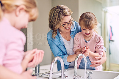 Buy stock photo Shot of a cheerful young mother and her young little daughter washing their hands together