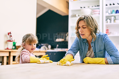 Buy stock photo Shot of a determined young mother and her young little daughter cleaning a table's surface together
