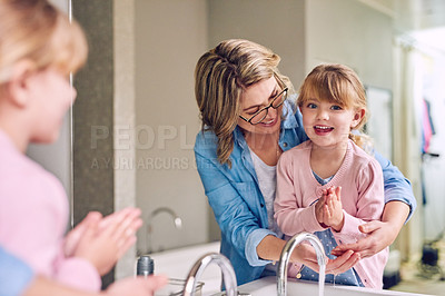 Buy stock photo Portrait of a cheerful young mother and her young little daughter washing their hands together