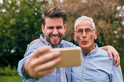 Buy stock photo Shot of a senior father and his adult son taking a selfie outside