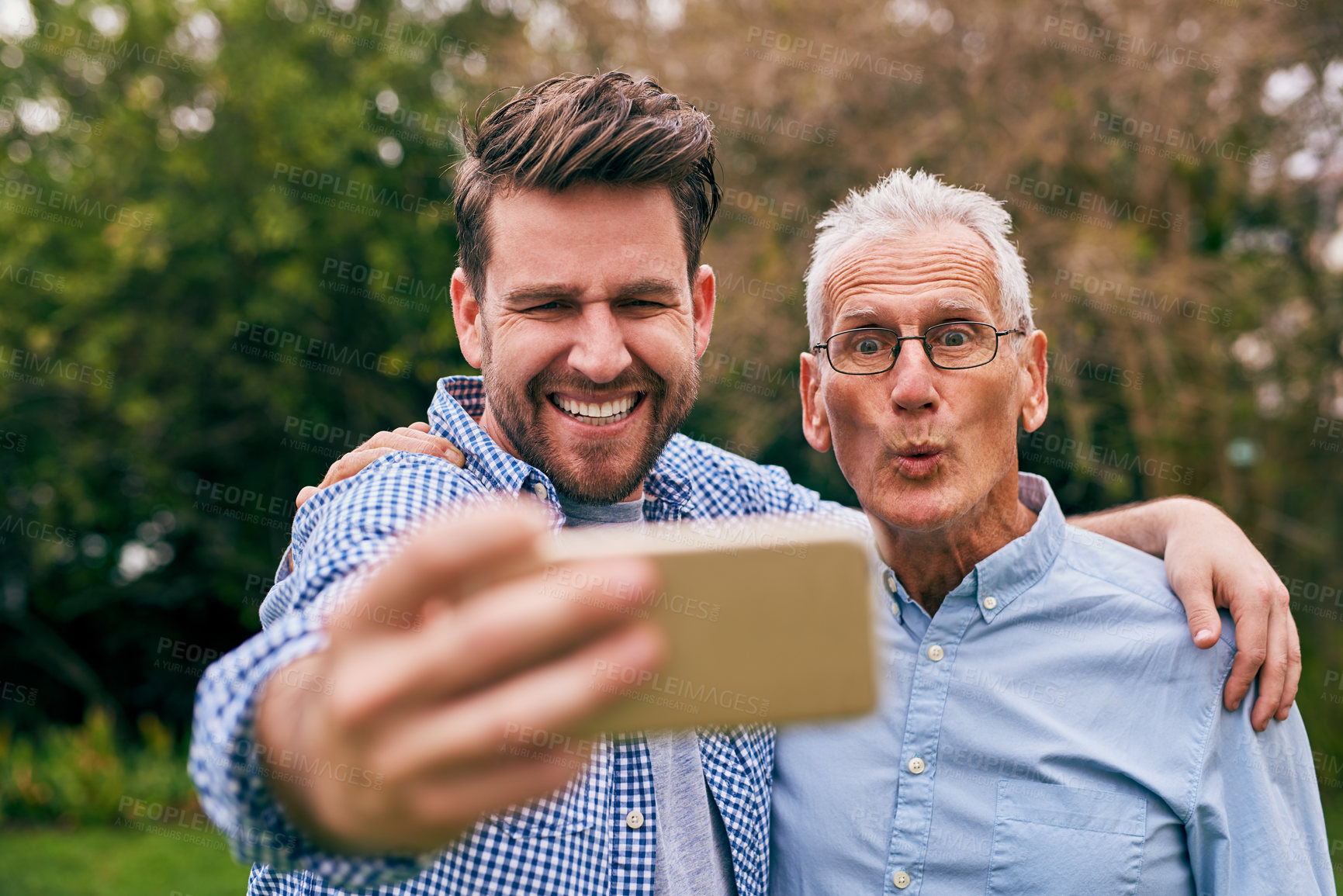 Buy stock photo Shot of a senior father and his adult son taking a selfie outside