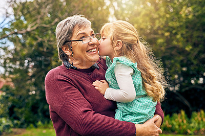 Buy stock photo Shot of a granddaughter kissing her grandmother on the cheek outside
