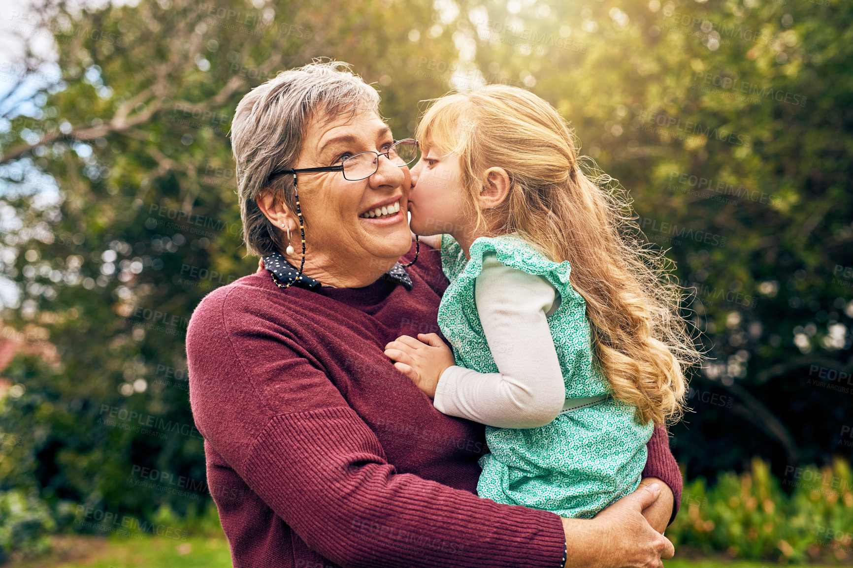 Buy stock photo Shot of a granddaughter kissing her grandmother on the cheek outside