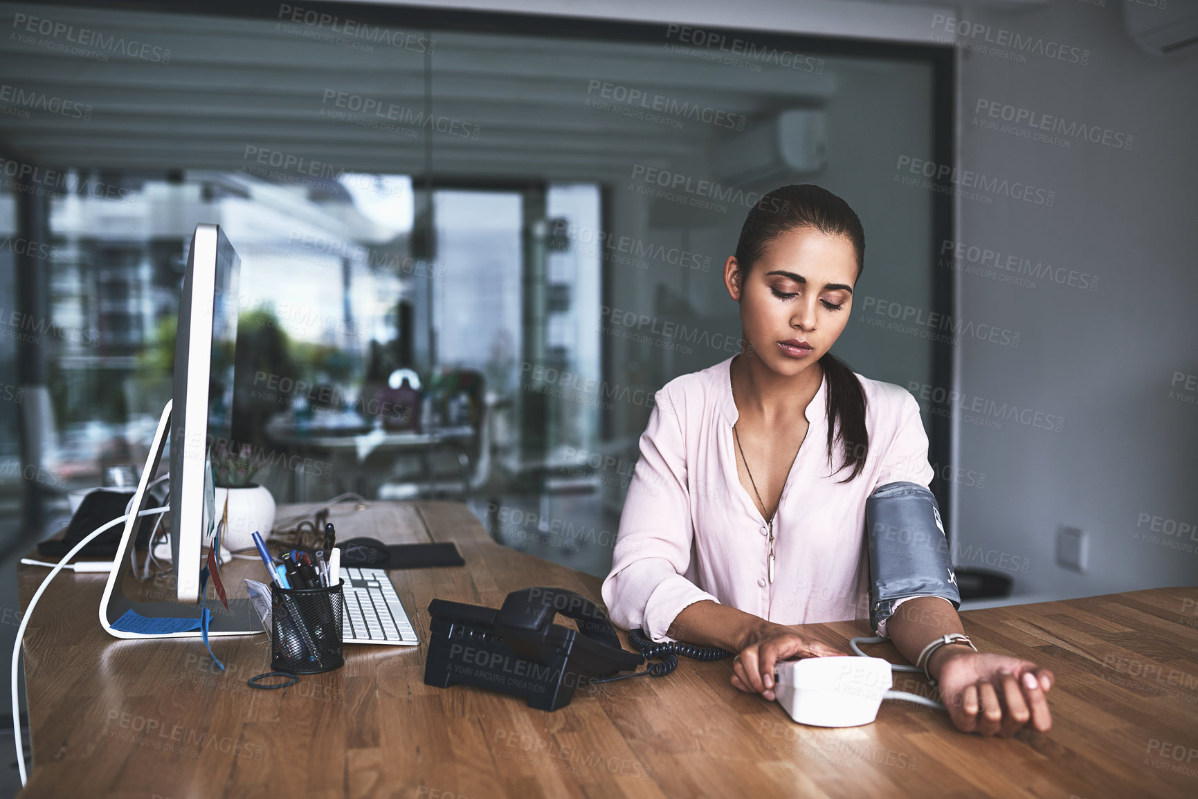 Buy stock photo Shot of a young businesswoman checking her blood pressure in an office