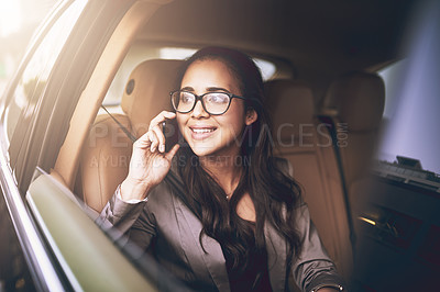 Buy stock photo Shot of a young businesswoman talking on a cellphone in the backseat of a car
