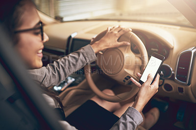 Buy stock photo Shot of a young businesswoman using a cellphone while driving a car